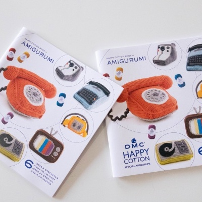 Dois livros com imagens de objetos em amigurumi coloridos e texto DMC HAPPY COTTON