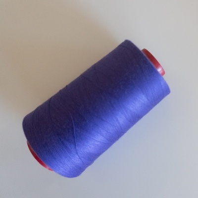 Rolo de linha de costura roxa sobre superfície branca