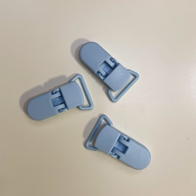 Três prendedores de plástico azul claro em superfície branca