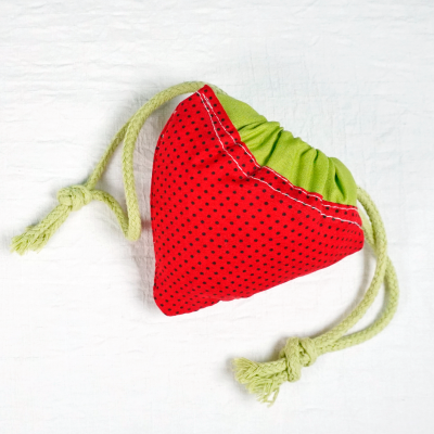 Saco pequeno de tecido vermelho com pontos pretos e parte verde com cordões para fechar