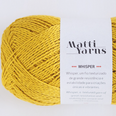 Novelo de fio amarelo texturizado com etiqueta branca da marca Matti Yarns e descrição Whisper