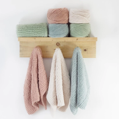 Toalhas penduradas e novelos de lã em suporte de madeira