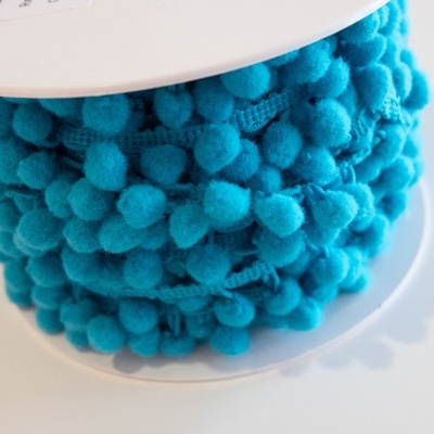 Rolo de fita de pompons azuis em suporte branco