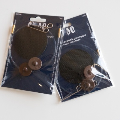 Remendos redondos pretos com botões castanhos em embalagem azul escura