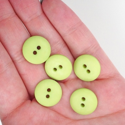 Cinco botões verdes claros com dois furos na palma de uma mão.