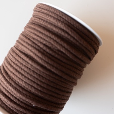 Rolo de cordão castanho enrolado num suporte branco
