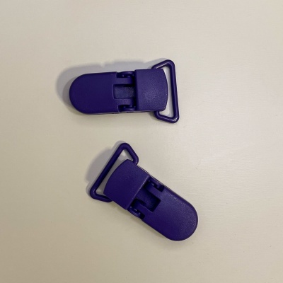 Dois clipes plásticos roxos com argola triangular numa superfície branca