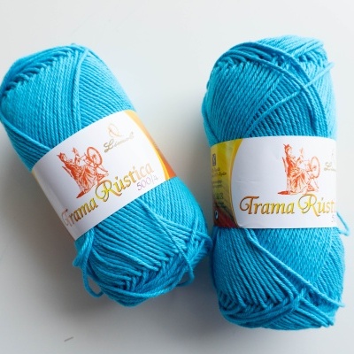 Dois novelos de lã azul turquesa com etiquetas da marca Grama Rústica