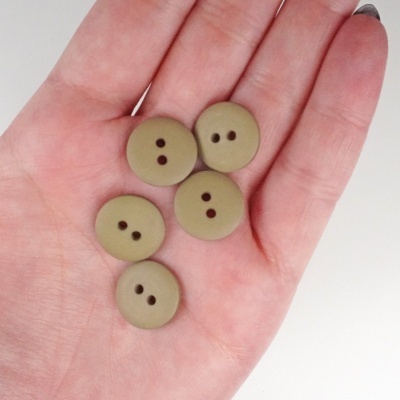 Cinco botões castanhos claros com dois furos na mão.