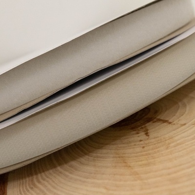 Dupla de roldanas de tecido bege sobre madeira clara com fundo branco.