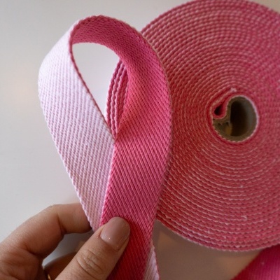 Rolo de fita têxtil rosa em duas tonalidades segurado por mão