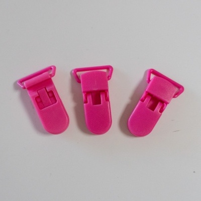 Três presilhas plásticas cor-de-rosa sobre fundo branco