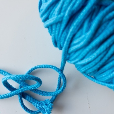 Bobina de fio azul grosso com textura trançada sobre superfície branca