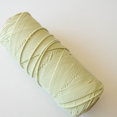 Rolo de fio macramé bege claro sobre fundo branco