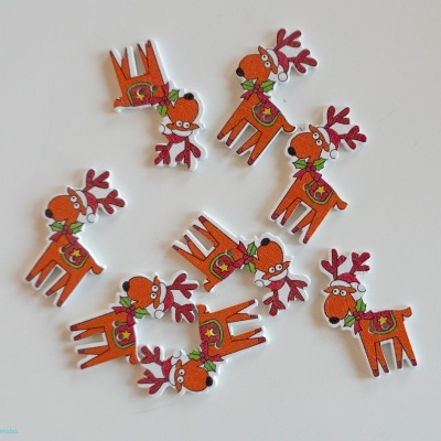 Pequenas decorações em madeira em forma de rena laranja sobre superfície branca