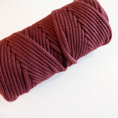 Rolo de corda trançada bordô sobre superfície branca