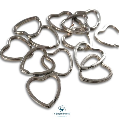 Arganéis metálicos prateados em forma de coração sobre fundo branco.