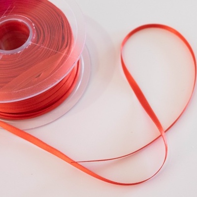 Rolo de fita vermelha em carretel de plástico transparente sobre superfície branca