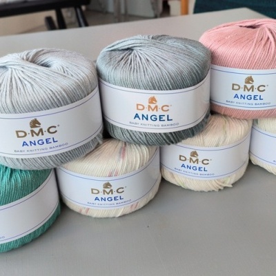 Sete novelos de fio para tricô DMC Angel Baby Knitting Bamboo em várias cores com etiquetas brancas.