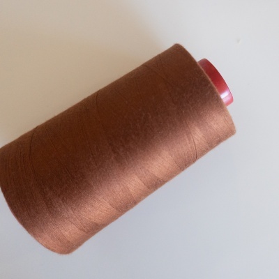 Carretel de linha castanha com eixo vermelho sobre fundo branco