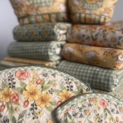 Tecidos e capas acolchoadas com padrão floral e xadrez em tons suaves