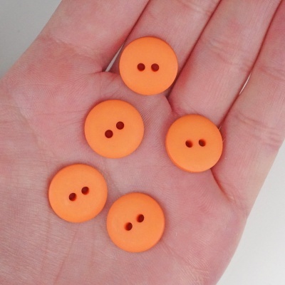 Cinco botões laranja com dois orifícios na palma da mão.