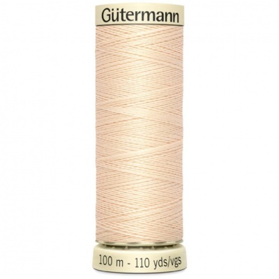 Spool of light peach Gütermann thread with labels on white background