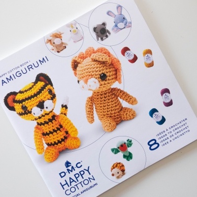 Livro ou folheto branco com bonecos de crochê amigurumi tigre e leão