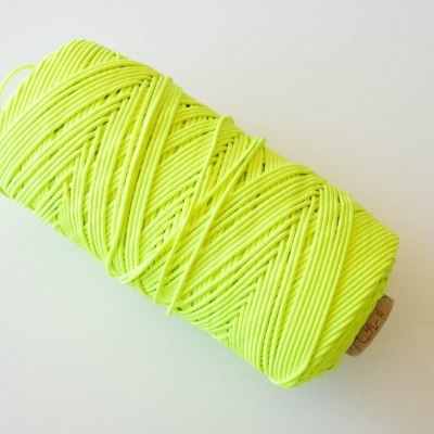 Rolo de corda amarelo fluorescente sobre superfície branca