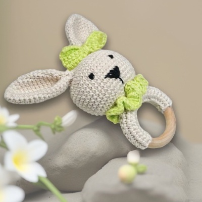 Chocalho para bebé com cabeça e orelhas de coelho em crochê cinzento claro, detalhes verdes e argola de madeira
