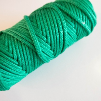 Rolo de cordão verde com textura entrelaçada sobre fundo branco
