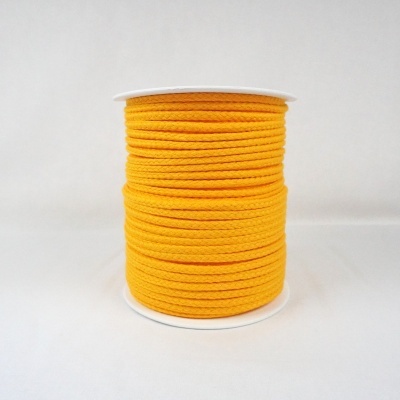 Rolo de cordão de tecido amarelo num carretel branco.