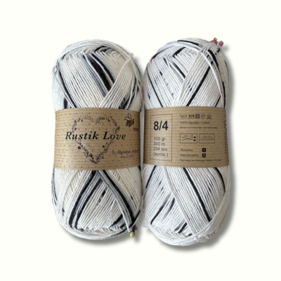 Dois novelos de fio algodão Rustik Love em tons cinza, branco e preto com etiquetas de papel reciclado