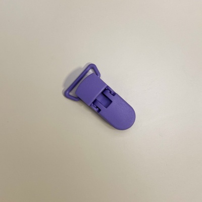 Clip roxo de plástico com mecanismo de fecho sobre superfície clara