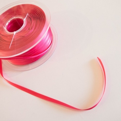 Rolo de fita vermelha fina desenrolada sobre superfície branca