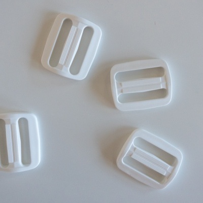 Quatro fivelas brancas de plástico em superfície branca