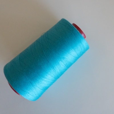 Rolo de linha azul turquesa num carretel vermelho