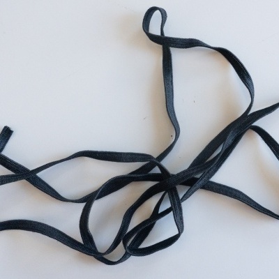 Correia elástica preta fina sobre superfície branca