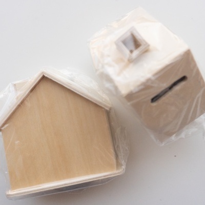 Duas caixas de madeira em forma de casa envolvidas em plástico transparente