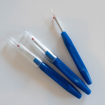 Três agulhas de crochê com cabos azuis e pontas metálicas em fundo branco.