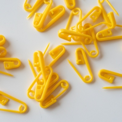 Alfinetes de plástico amarelo espalhados sobre fundo branco.