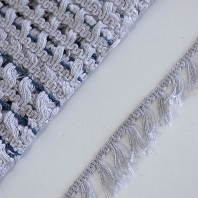 Tapete branco com padrão trançado e franja sobre superfície branca