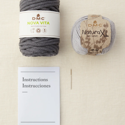 Dois novelos de fio de algodão DMC e manual de instruções sobre tecido claro