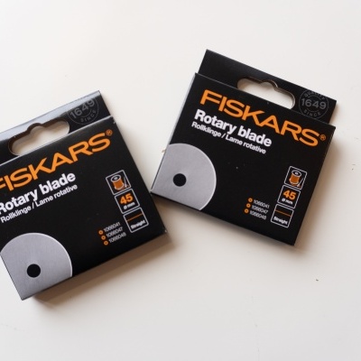 Duas caixas pretas de lâminas rotativas FISKARS de 45 mm sobre fundo branco