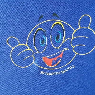 Camisola azul com desenho de sorriso amarelo e texto BY MARTIM SANTOS.