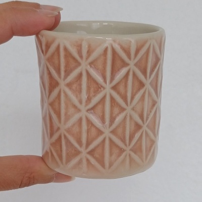 Caneca de cerâmica bege com padrão geométrico em relevo