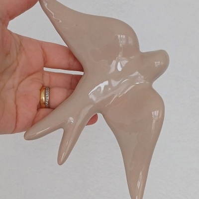 Pássaro decorativo em cerâmica bege brilhante na mão