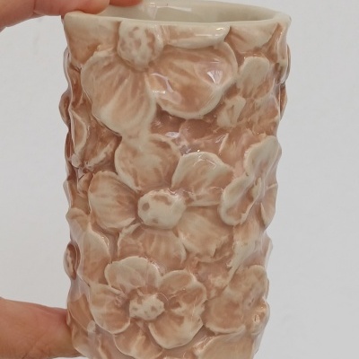 Vaso pequeno de cerâmica bege com flores em relevo e brilho