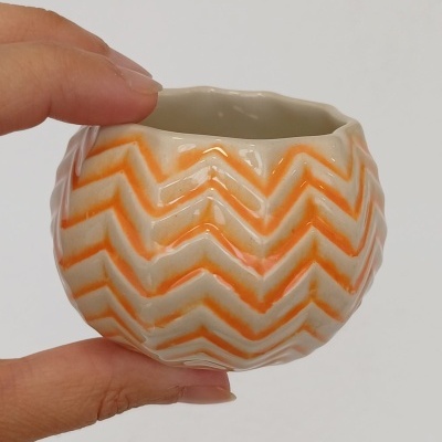 Pequeno vaso cerâmico branco com padrão vermelho em ziguezague