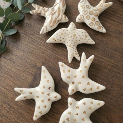 Peças decorativas em cerâmica branca com desenhos dourados em forma de pássaros